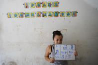 Gabriela Fajardo, a 26-year-old Honduran seeking asylum in the United States, teaches a Zoom class for Central American children living in camps, various shelters and apartments in other parts of Mexico on Friday, Nov. 20, 2020, from a hallway of an aged building in Matamoros, Mexico. Like countless schools, the sidewalk school, as it became known, went to virtual learning amid the coronavirus pandemic, but instead of being hampered by the change, it has blossomed. (AP Photo/Eric Gay)