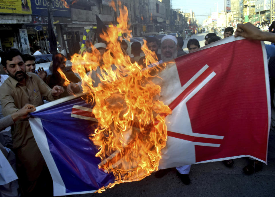 Pakistan traders burn burn a representation of the French flag during a protest against the publishing of caricatures of the Prophet Muhammad they deem blasphemous, in Peshawar, Pakistan, Monday, Oct. 26, 2020. Pakistan's Prime Minister Imran Khan said the French leader chose to encourage anti-Muslim sentiment and deliberately provoke Muslims by encouraging the display of blasphemous cartoons targeting Islam. (AP Photo/Muhammad Sajjad)