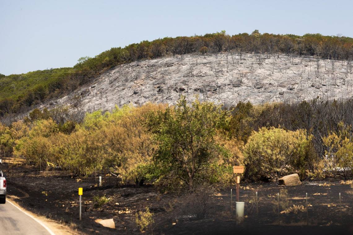 A hillside is scarred as a fire blazes along FM 1148 on Tuesday, July 19, 2022, near Possum Kingdom Lake in Graham. The fire had consumed 500 acres and was 10 percent contained.