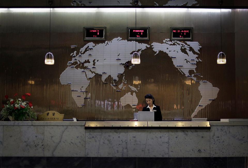 A hotel staff member stands at a reception desk decorated with a map of the world on Oct. 23, 2014, in Pyongyang, North Korea.
