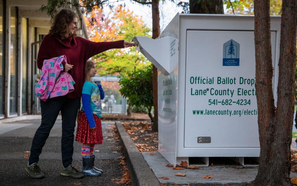 Katie Petersen votes over her daughter Lilyanah Sutton at the Lane County Elections drop box on in November 2020 in Eugene.