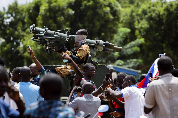 Soldiers loyal to Capt. Ibrahim Traore are cheered in the streets of Ouagadougou, Burkina Faso, Sunday, Oct. 2, 2022. Burkina Faso's new junta leadership is calling for calm after the French Embassy and other buildings were attacked. (AP Photo/Kilaye Bationo)