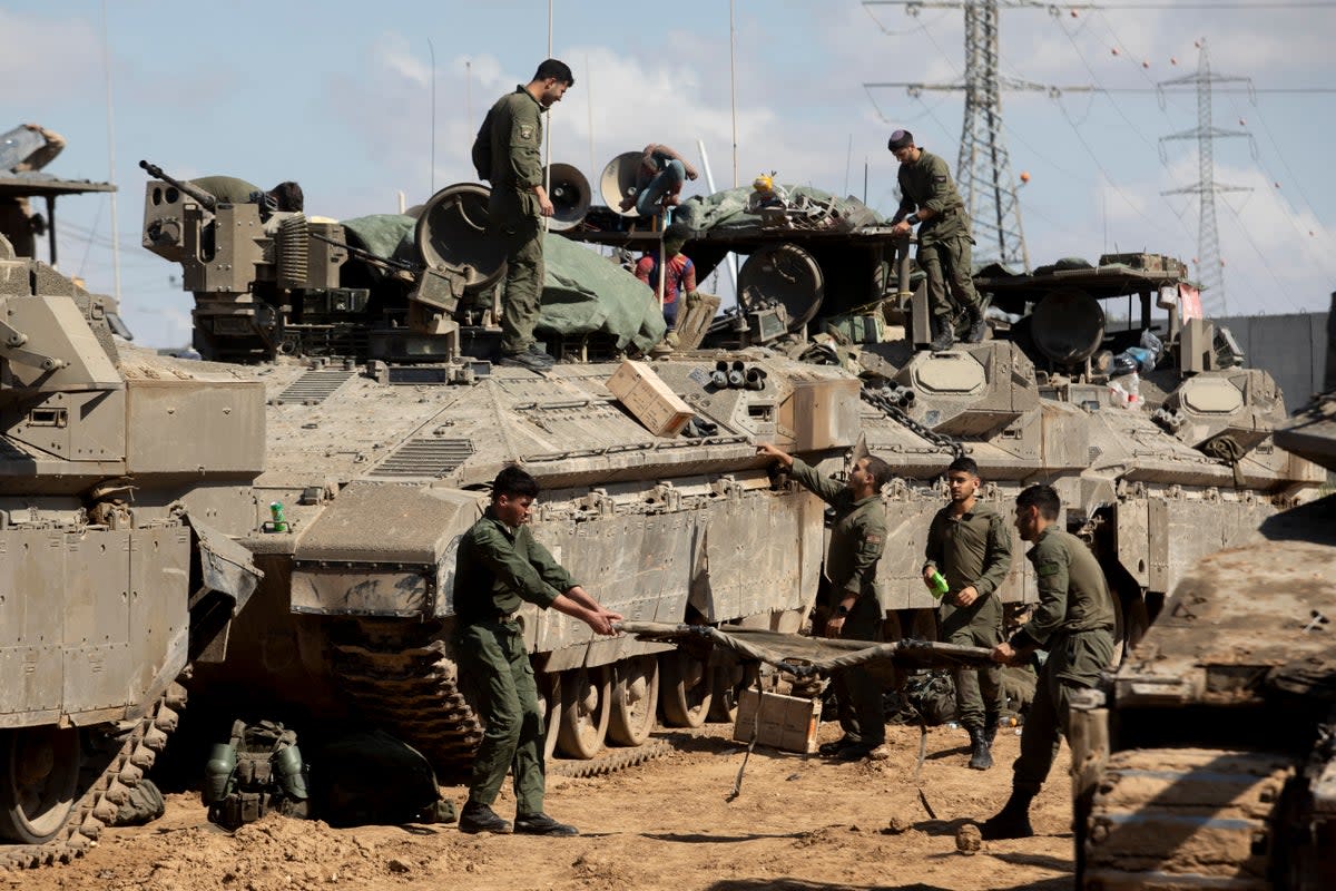 Israeli soldiers  prepare their equipment and armoured personnel carriers before entering the Gaza Strip (Getty Images)