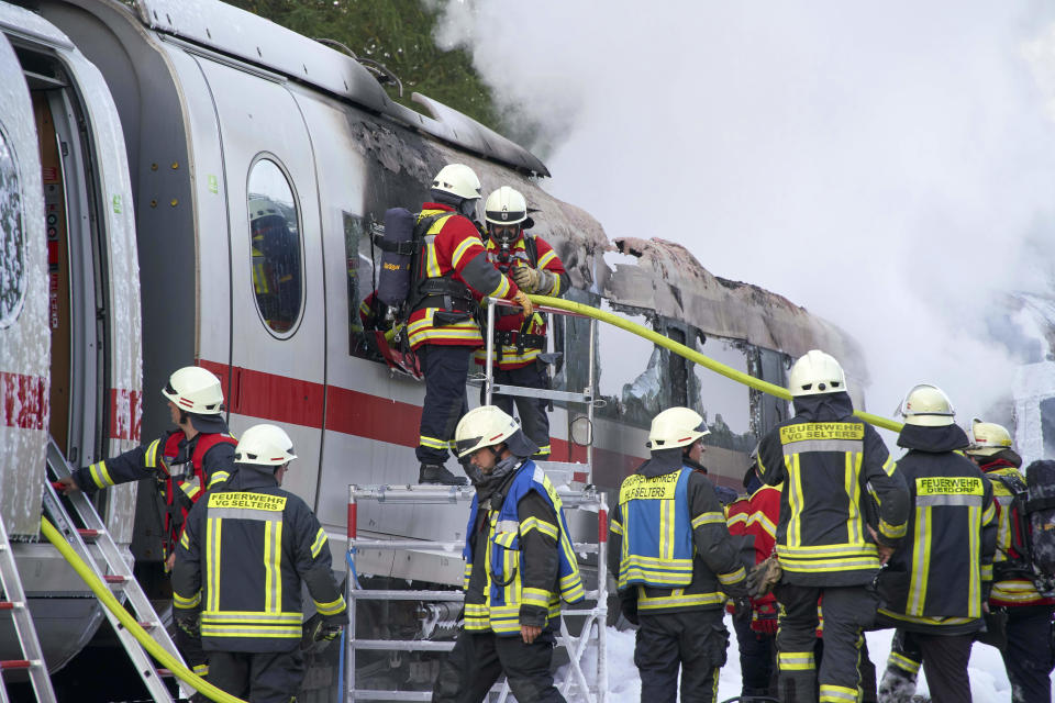 Firefighters extinguish flames in a burning ICE high-speed train in Dierdorf near Montabaur, western Germany, Friday, Oct. 12, 2018 after a part caught fire for unknown reasons. No passenger was injured. (Sascha Ditscher/dpa via AP)