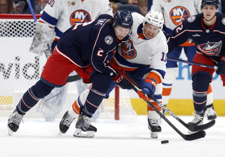 Columbus Blue Jackets defenseman Andrew Peeke, left, reaches for the puck in front of New York Islanders forward Zach Parise during the first period of an NHL hockey game in Columbus, Ohio, Friday, Nov. 25, 2022. (AP Photo/Paul Vernon)