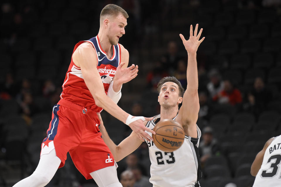 Washington Wizards' Kristaps Porzingis, left, passes the ball as he is defended by San Antonio Spurs' Zach Collins (23) during the first half of an NBA basketball game, Monday, Jan. 30, 2023, in San Antonio. (AP Photo/Darren Abate)