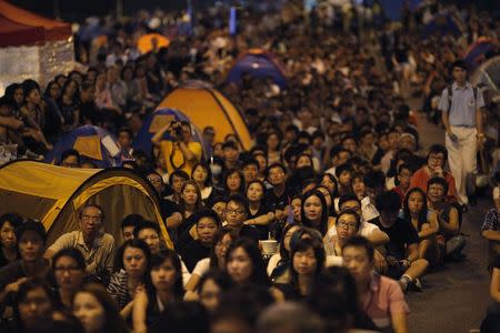 Pro-democracy protestors watch formal talks between student protest leaders and city officials on a video screen near the government headquarters in Hong Kong October 21, 2014. REUTERS/Carlos Barria