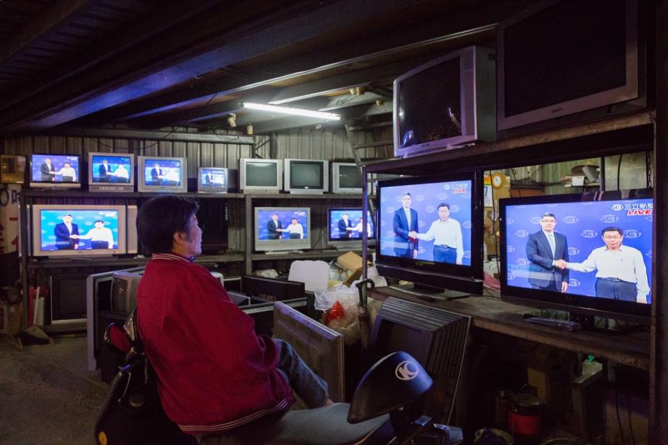 2014年11月7日，台北市長候選人連勝文、柯文哲出席電視辯論會，路邊店家播放著，民眾駐足觀看。（林后駿攝）