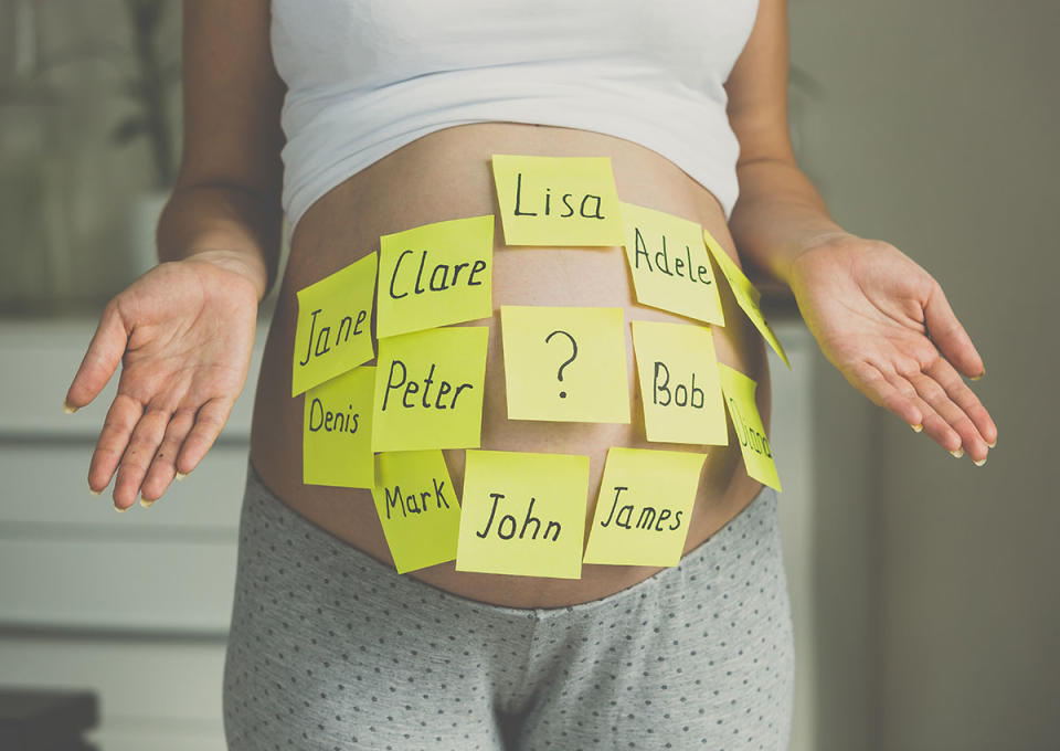 Pregnant woman with post it notes on her stomach with names. 