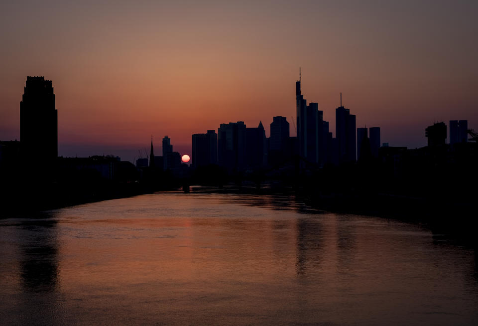 The sun sets behind the buildings of the banking district in Frankfurt, Germany, Saturday, March 28, 2020. Due to the coronavirus the economy expects heavy losses worldwide. For most people, the new coronavirus causes only mild or moderate symptoms, such as fever and cough. For some, especially older adults and people with existing health problems, it can cause more severe illness, including pneumonia.(AP Photo/Michael Probst)