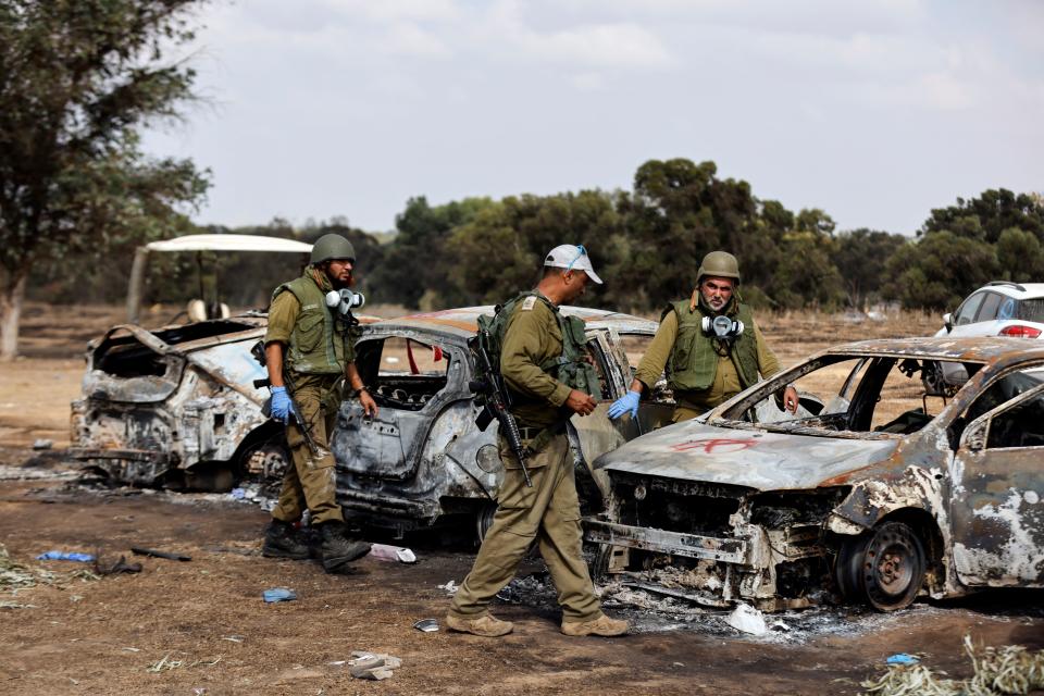 Israeli soldiers inspect burnt cars