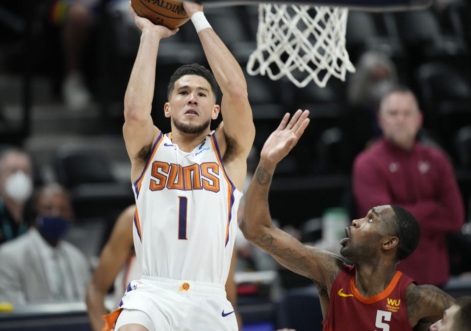 Phoenix Suns guard Devin Booker, left, goes up for a basket as Denver Nuggets forward Will Barton defends in the first half of Game 4 of an NBA second-round playoff series Sunday, June 13, 2021, in Denver. (AP Photo/David Zalubowski)