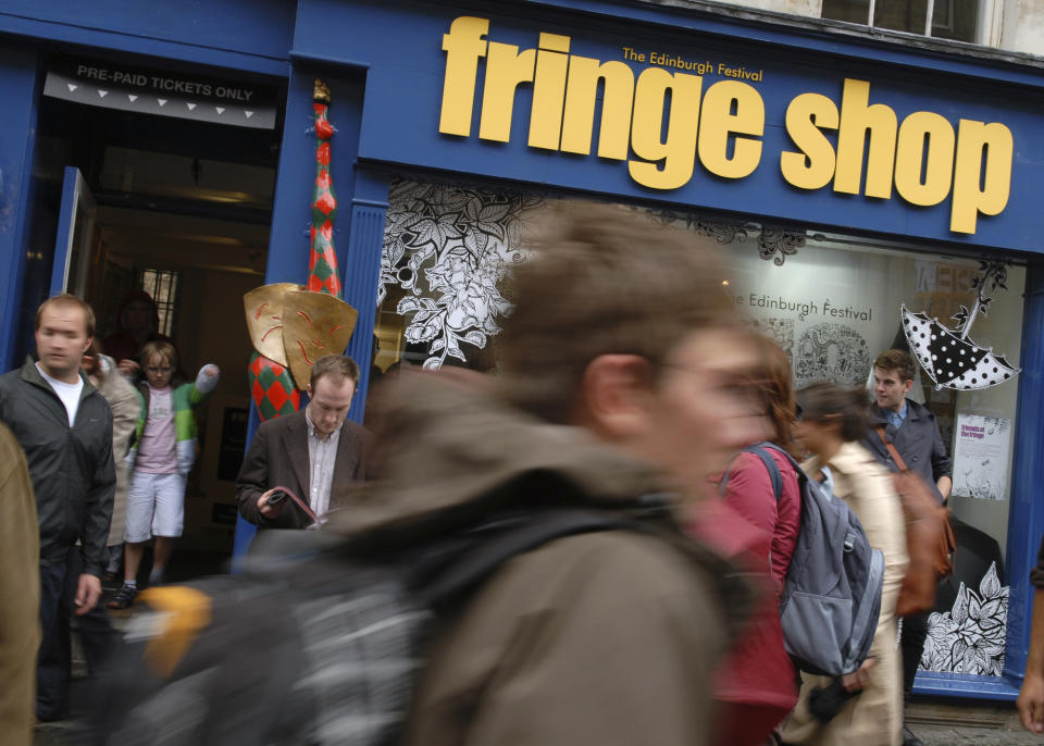 FILE - In this Friday, Aug. 6, 2010 file photo, people pass the Fringe Shop on Edinburgh's Royal Mile on the first day of the Edinburgh Fringe. Every August, the Scottish capital of Edinburgh plays host to some of the funniest and talented — not to forget the strangest — artists from the U.K. and the wider world. Not this year, as organizers made the decision Wednesday, April 1, 2020 to cancel the city's festivals as a result of the coronavirus pandemic. (AP Photo/Scott Campbell, File)