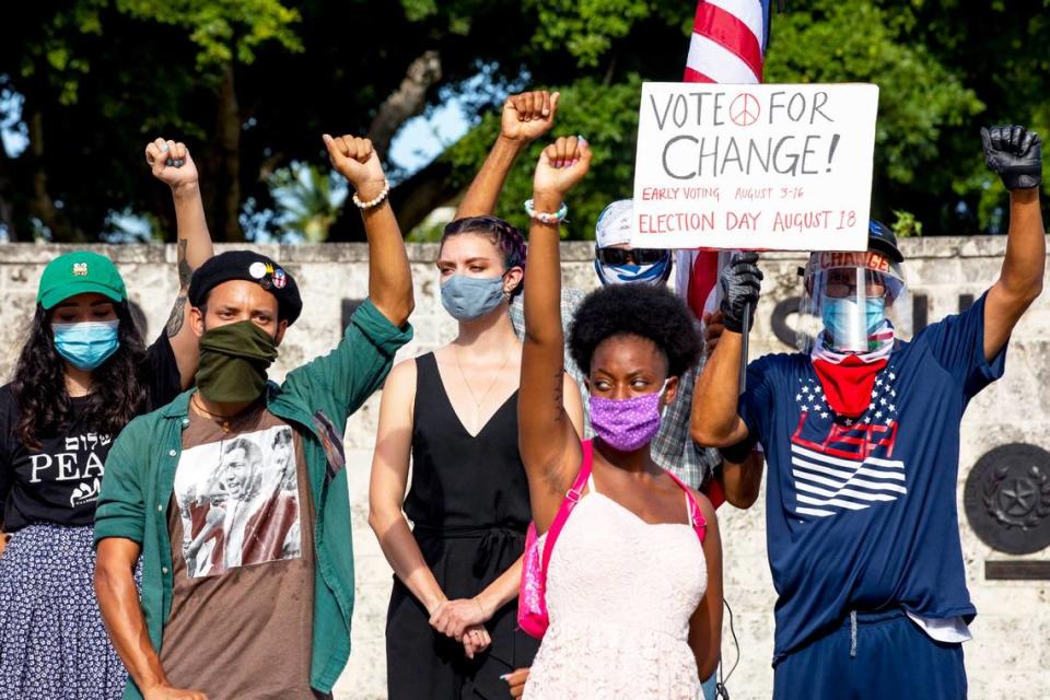 Acitvists pose with their fists in the air as an act of solidarity while speakers share their experiences of getting arrested while protesting peacefully, during a Black Lives Matter protest to denounce the recent police brutality the local organizers have faced, at The Torch of Friendship in Miami, Florida on Tuesday, July 28, 2020.