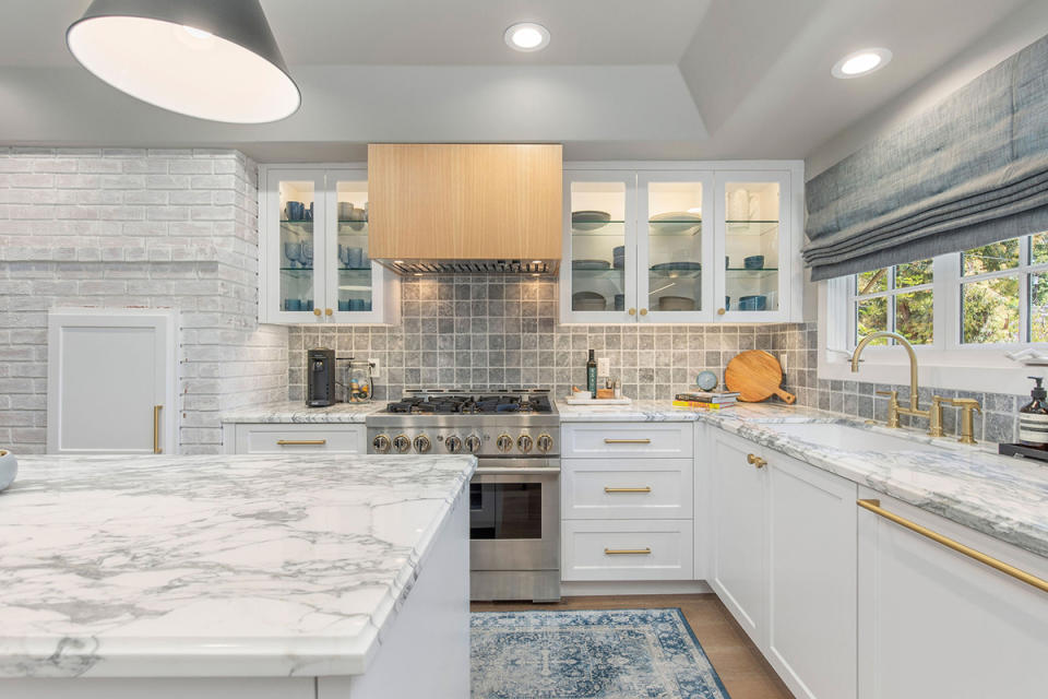 The open-plan kitchen employs trendy brass fixtures and stone-like counters.