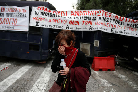 A protester covers her face to protect from tear gas as Greek school teachers scuffle with riot police during a demonstration against government plans to change hiring procedures in the public sector in Athens, Greece, January 11, 2019. REUTERS/Costas Baltas