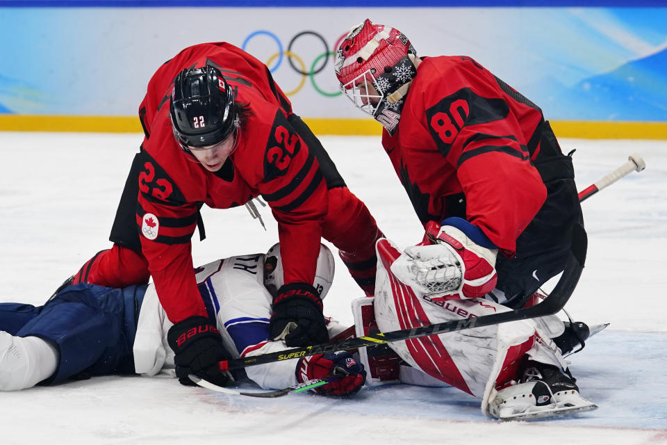Canada goalkeeper Eddie Pasquale (80) and Owen Power (22) stop United States' Nathan Smith from reaching the puck during a preliminary round men's hockey game at the 2022 Winter Olympics, Saturday, Feb. 12, 2022, in Beijing. (AP Photo/Matt Slocum)