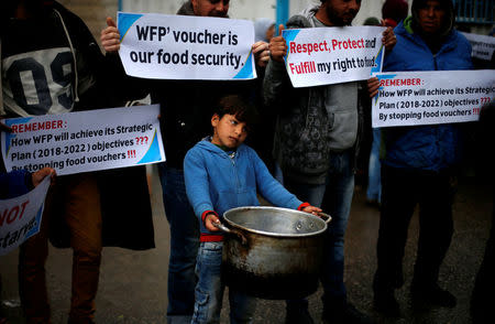 A Palestinian boy carries a cooking pot during a protest against aid cut, outside United Nations' offices in Gaza City January 17, 2018. REUTERS/Suhaib Salem