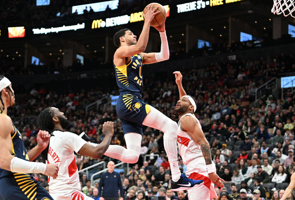 Apr 9, 2024; Toronto, Ontario, CAN; Indiana Pacers guard Tyrese Haliburton (0) drives to the basket over Toronto Raptors guard Javon Freeman-Liberty (0) and Bruce Brown (11) in the second half at Scotiabank Arena. Mandatory Credit: Dan Hamilton-USA TODAY Sports