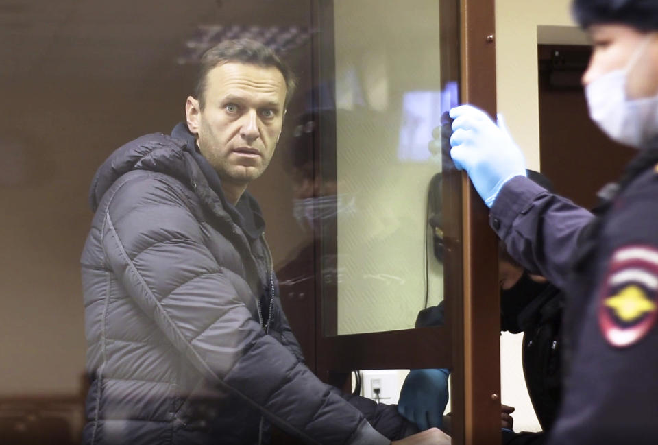 In this image made from video provided by the Babuskinsky District Court, Russian opposition leader Alexei Navalny stands in a cage during a hearing on his charges for defamation, in the Babuskinsky District Court in Moscow, Russia, Friday, Feb. 5, 2021. Navalny was accused of slandering a World War II veteran featured in the video promoting the constitutional reform allowing to extend President Vladimir Putin's rule. The politician slammed people in the video as "corrupt stooges" and "traitors." (Babuskinsky District Court via AP)