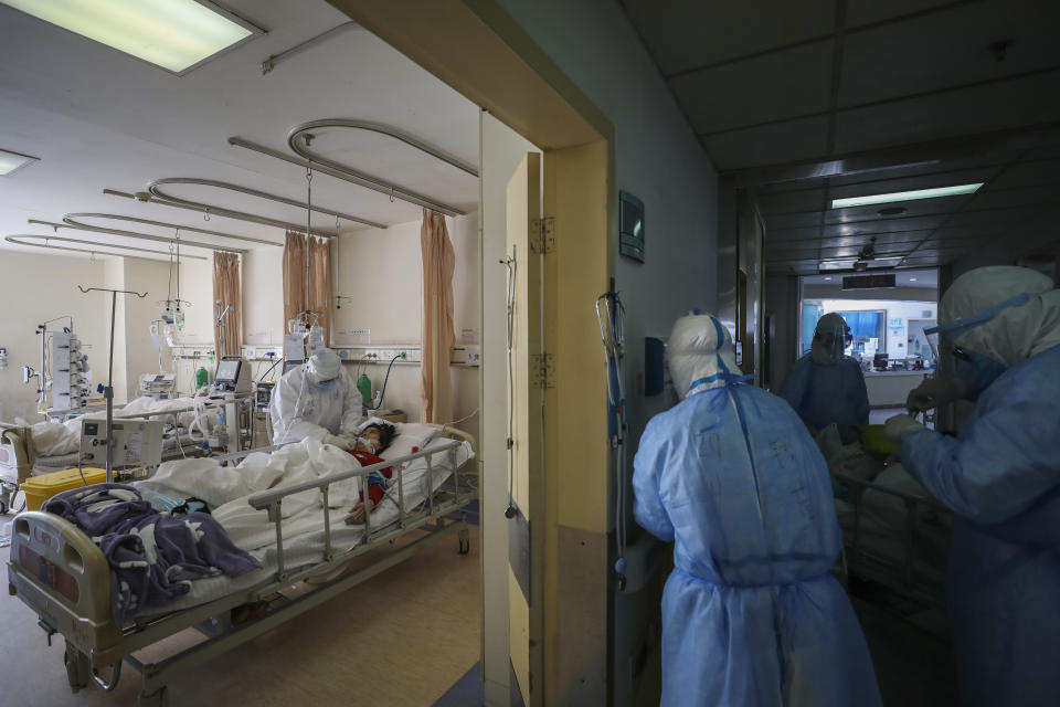 In this Sunday, Feb. 16, 2020, photo, medical personnel provide treatment to a a new coronavirus patient at a hospital in Wuhan in central China's Hubei province. Chinese authorities on Monday reported a slight upturn in new virus cases and hundred more deaths for a total of thousands since the outbreak began two months ago. (Chinatopix via AP)