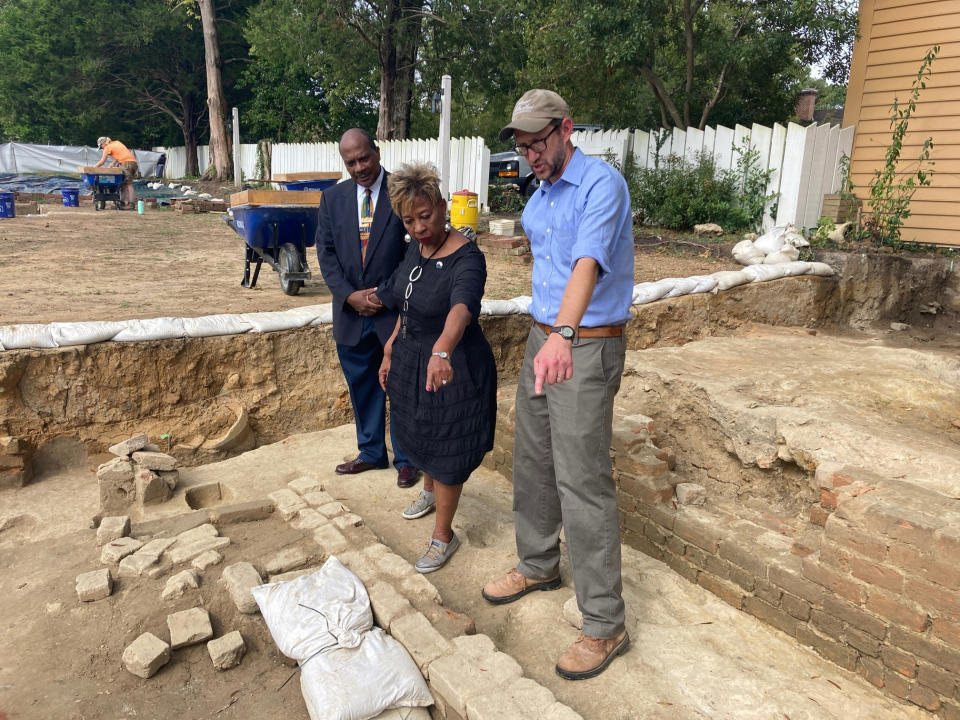 Reginald F. Davis, from left, pastor of First Baptist Church in Williamsburg, Connie Matthews Harshaw, a member of First Baptist, and Jack Gary, Colonial Williamsburg's director of archaeology, stand at the brick-and-mortar foundation of one the oldest Black churches in the U.S. on Wednesday, Oct. 6, 2021, in Williamsburg, Va. Colonial Williamsburg announced Thursday Oct. 7, that the foundation had been unearthed by archeologists. (AP Photo/Ben Finley)