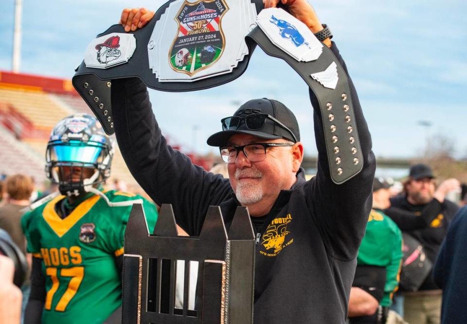 Law Hogs coach Mike Morris holds up a victory belt behind the Pig Bowl Guns vs Hoses trophy after the 50th anniversary game at Hughes Stadium on Saturday. The former Rio Linda High School coach finished his Pig Bowl career with a 9-3 record. Nathaniel Levine/nlevine@sacbee.com