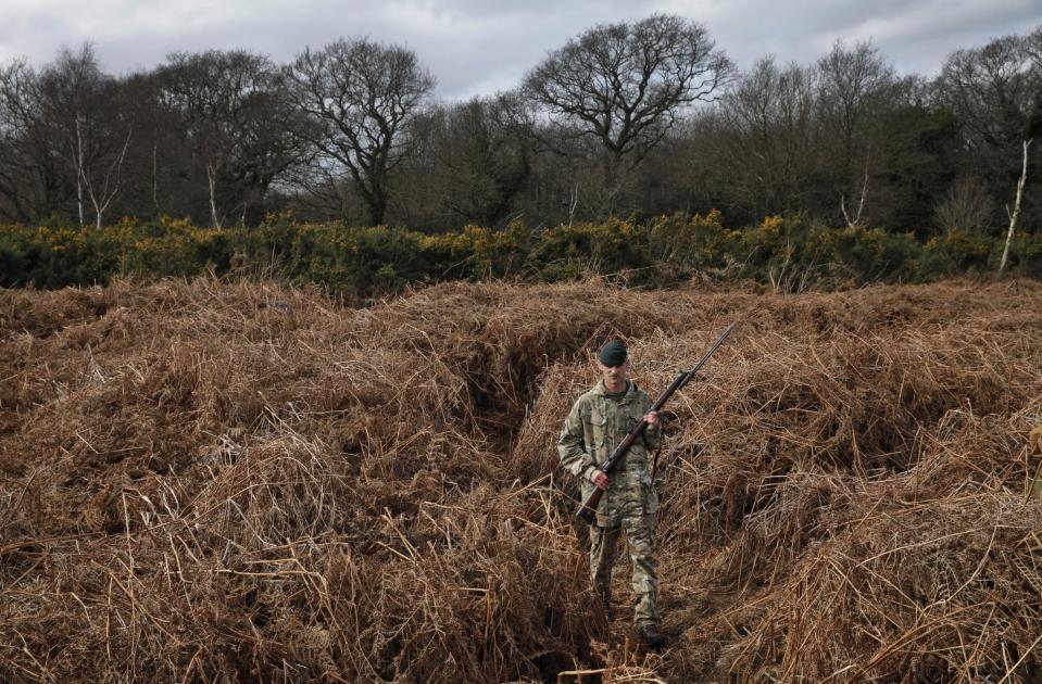 British army Rifleman Stuart Gray walks on a WW1 practise trench as he poses for the photographers in Gosport, southern England, Thursday, March 6, 2014. This overgrown and oddly corrugated patch of heathland on England’s south coast was once a practice battlefield, complete with trenches, weapons and barbed wire. Thousands of troops trained here to take on the Germany army. After the 1918 victory _ which cost 1 million Britons their lives _ the site was forgotten, until it was recently rediscovered by a local official with an interest in military history. Now the trenches are being used to reveal how the Great War transformed Britain _ physically as well as socially. As living memories of the conflict fade, historians hope these physical traces can help preserve the story of the war for future generations. (AP Photo/Lefteris Pitarakis)