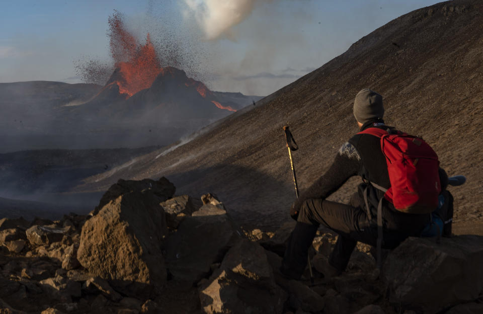 A man watches as lava spews from an eruption of the Fagradalsfjall volcano on the Reykjanes Peninsula in southwestern Iceland on Tuesday, May 11, 2021. (AP Photo/Miguel Morenatti)