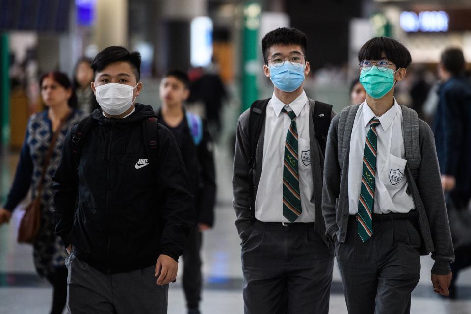 Young students wear face masks in the arrivals hall at Hong Kong's international airport on January 22, 2020, after China recently confirmed human-to-human transmission in the outbreak of the new SARS-like virus. - A new virus that has killed nine people, infected hundreds and already reached the United States could mutate and spread, China warned on January 22, as authorities scrambled to contain the disease during the Lunar New Year travel season. (Photo by Anthony WALLACE / AFP) (Photo by ANTHONY WALLACE/AFP via Getty Images)