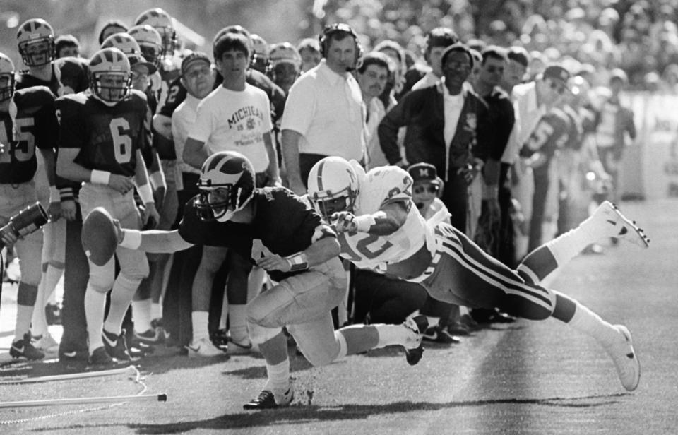 Michigan quarterback Jim Harbaugh runs to the sidelines with the ball while being pursued by Nebraska tackle Neil Smith during the third quarter of the Fiesta Bowl in Tempe, Ariz., Jan. 1, 1986. Michigan defeated Nebraska, 27-23.
