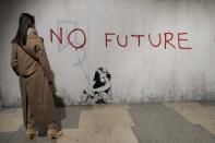 A visitor walks past "No Future", a reproduction of a mural by British artist Banksy, during the unveiling of the "The World of Banksy, The Immersive Experience" exhibition, in Milan, Italy, Thursday, Dec. 2, 2021. An exhibition of 130 works by British street artist Banksy opens Friday in a gallery space inside Milan's Central train Station. The exhibition unveiled on Thursday includes 30 never before seen works by Bansky and highlights pieces by young unknown artists from all over Europe. (AP Photo/Luca Bruno)