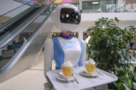 Robotic waiter Claire, delivers an order to customers at the Robot Cafe in Nairobi, Kenya Thursday, Aug. 29, 2024. The three robots, christened Claire, R24 and Nadia, are not programmed to have a full conversation with customers, but they can say "Your order is ready, Welcome" then people have to press an exit button after picking up their food from the tray. (AP Photo/Brian Inganga)