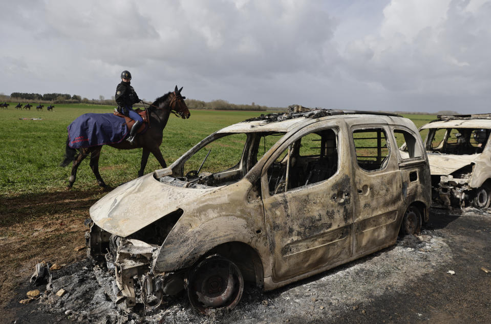 FILE - A mounted police officer rides past burned-out police vehicles next to the construction site of an agricultural reservoir after clashes with protesters in Sainte-Soline, western France, Sunday March 26, 2023. French President Emmanuel Macron presents Thursday March 30, 2023 a plan for saving France's water after exceptional winter drought, February wildfires and violence between protesters and police over an agricultural reservoir. (AP Photo/Jeremias Gonzalez, File)