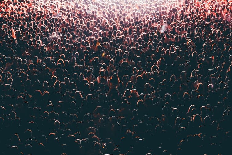 Colorful crowd of people of a big music festival in a stage lights as a beautiful background