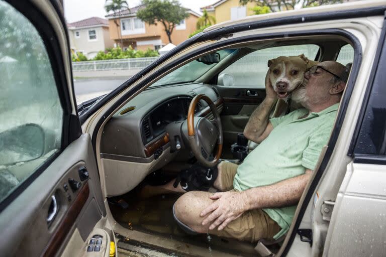 Mike Viesel besa a su perro, Humi, mientras esperan en su coche inundado a una grúa después de que su coche se quedara parado en la calle Taft debido a las fuertes lluvias que inundaron el barrio el miércoles 12 de junio de 2024, en Hollywood, Florida.