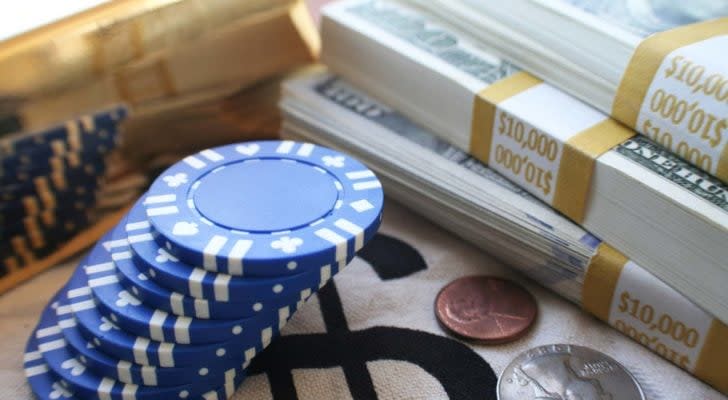 Blue poker chips stacked next to three stacks of $100 bills representing blue chip stocks