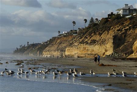 People walk along the beach in San Diego's North County beach town of Encinitas, California March 31, 2014. REUTERS/Mike Blake