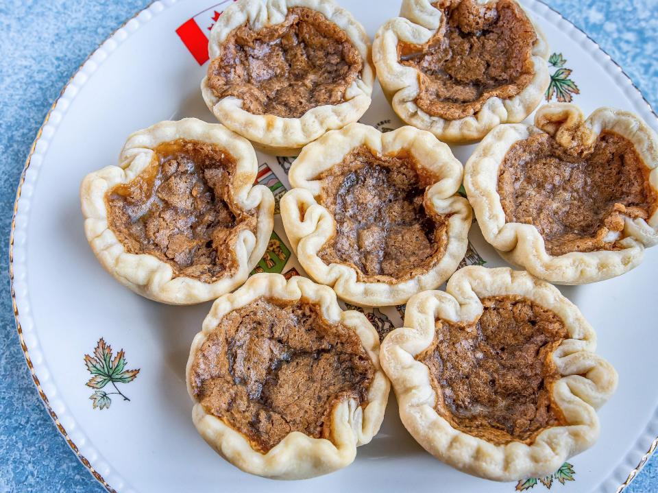 Seven butter tarts arranged on a plate