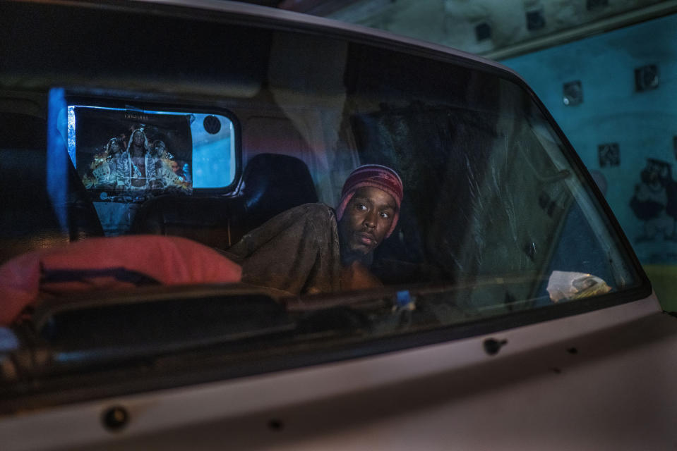 A man living in his car reacts to police and army patrolling downtown Johannesburg, South Africa, March 27, 2020. Police and army started patrolling moments after South Africa went into a nationwide lockdown. (AP Photo/Jerome Delay)