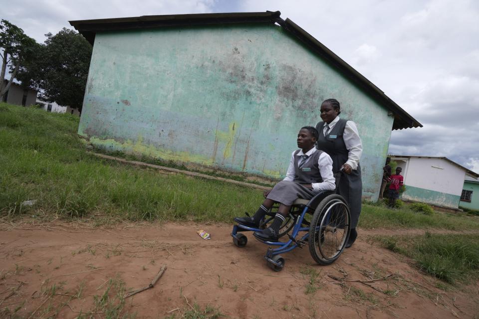 Bridget Chanda, right, pushes her friend Juliet Nankamba, in a wheelchair at Chileshe Chepela Special School in Kasama, Zambia, Wednesday, March 6, 2024. Chanda is intent on helping educate Zambia’s deaf community about climate change. As the southern African nation has suffered from more frequent extreme weather, including its current severe drought, it’s prompted the Zambian government to include more climate change education in its school curriculum. (AP Photo/Tsvangirayi Mukwazhi)