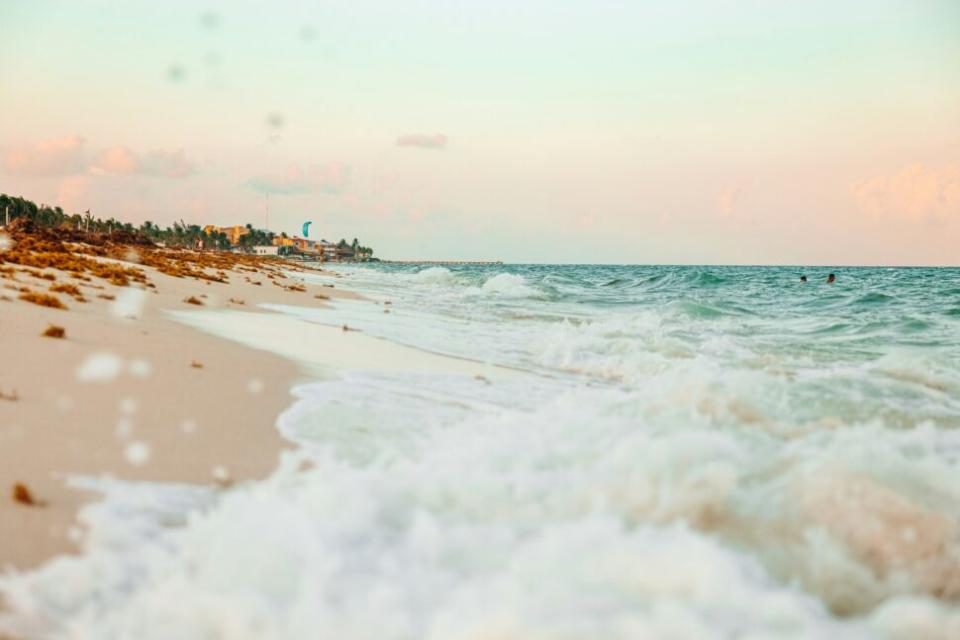 Check out this overview of the safety in Playa del Carmen and how travelers can have safe and comfortable trips. pictured: a close up on the turquoise waves of a Playa del Carmen beach near sunset on a clear day