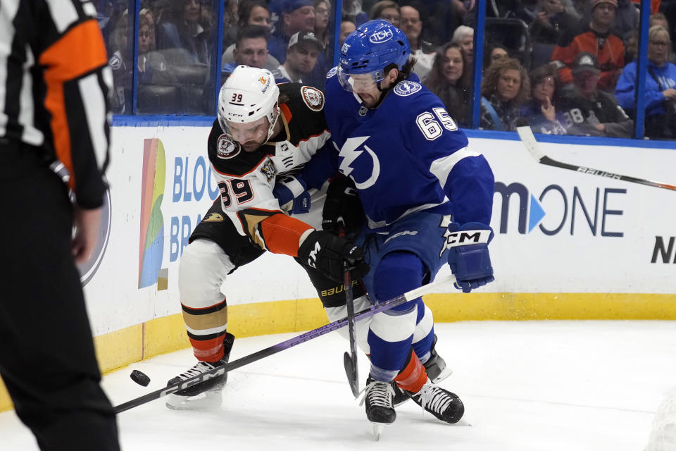 Tampa Bay Lightning defenseman Maxwell Crozier (65) checks Anaheim Ducks center Sam Carrick (39) into the dasher during the first period of an NHL hockey game Saturday, Jan. 13, 2024, in Tampa, Fla. (AP Photo/Chris O'Meara)