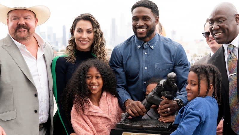 Former USC football player Reggie Bush poses with his attorneys, left, Levi McCathern and Ben Crump, right, along with his family and his Heisman trophy during a news conference at the Los Angeles Memorial Coliseum, Thursday, April, 25, 2024, in Los Angeles.