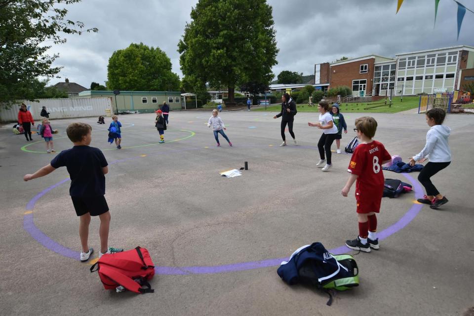 Children dance on a painted socially distanced circle in the playground as they wait to be picked up by their parents at Llanishen Fach Primary School in Cardiff: PA