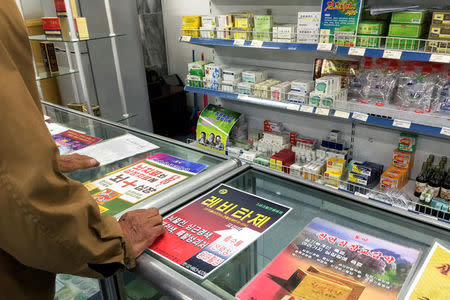 A man looks at advertising posters describing pharmaceuticals in a shop in Pyongyang, North Korea May 4, 2016. REUTERS/James Pearson