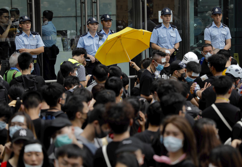 A protester holds out a yellow umbrella towards a line of police officers in Hong Kong Friday, June 21, 2019. Several hundred mainly student protesters gathered outside Hong Kong government offices Friday morning, with some blocking traffic on a major thoroughfare, after a deadline passed for meeting their demands related to controversial extradition legislation that many see as eroding the territory's judicial independence. (AP Photo/Vincent Yu)