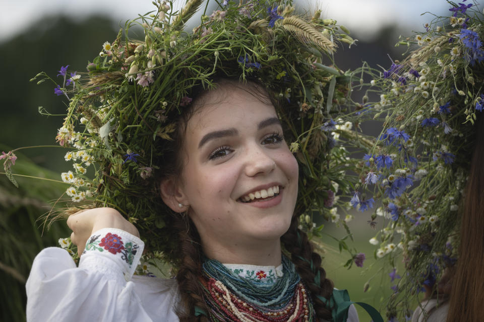 A girl with a ritual garland headdress smiles during a traditional Midsummer Night celebration near capital Kyiv, Ukraine, Sunday, June 23, 2024. The age-old pagan festival is still celebrated in Ukraine amid the third year of Russia-Ukraine war. (AP Photo/Efrem Lukatsky)