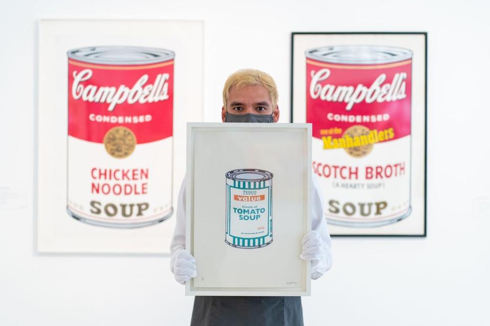 A Christie’s employee holds Soup Can – White/Emerald/Tan by Banksy (Dominic Lipinski/PA) (PA Wire)