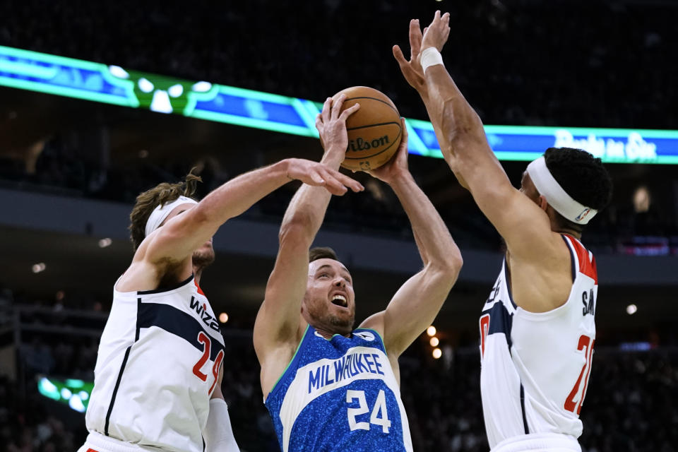 Milwaukee Bucks' Pat Connaughton, middle, shoots between Washington Wizards' Corey Kispert, left, and Landry Shamet during the first half of an NBA basketball In-Season Tournament game Friday, Nov. 24, 2023, in Milwaukee. (AP Photo/Aaron Gash)